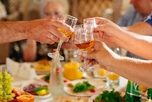 hands with glasses of drinks above the festive table. 