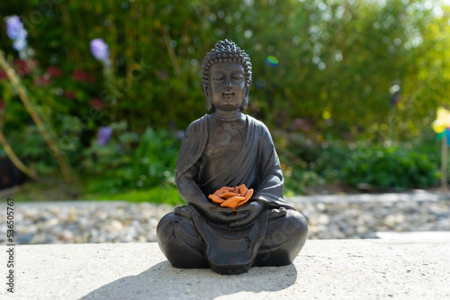 Buddha statue near house in front of garden.