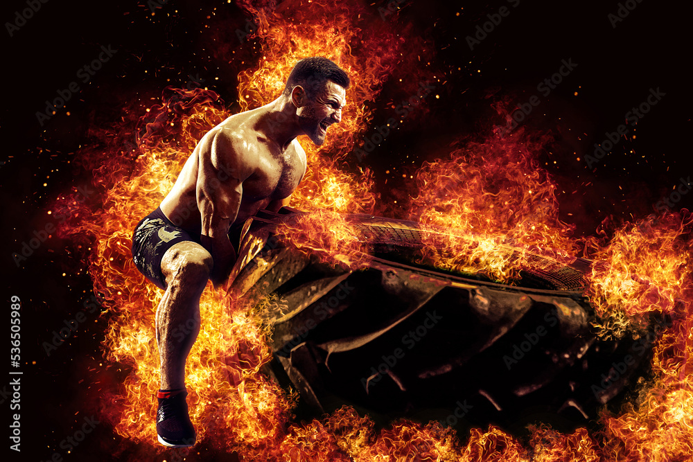 Muscular fitness shirtless man moving large tire in flames, concept lifting, workout cross training Muscular fitness shirtless man moving large tire in flames, concept lifting, workout cross training
