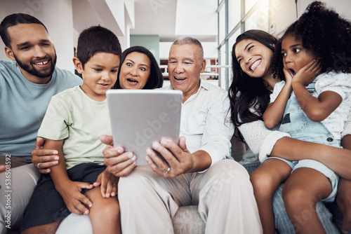 Family, home and fun people with tablet streaming a movie, subscription video or show online. Love, surprise and happy big family on a sofa smile while bonding, relax and enjoy quality time together