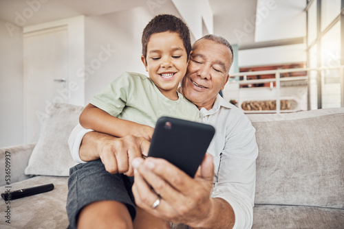 Grandfather, kid and phone on sofa in home playing games or old man learning social media from boy. Love, relax and grandpa with child on 5g mobile, app or smartphone web surfing and bonding together