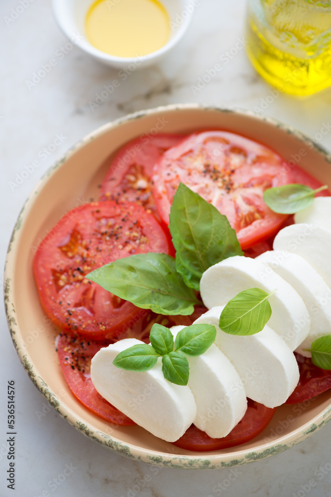 Closeup of sliced mozzarella cheese with red tomatoes and green basil, vertical shot, selective focus Closeup of sliced mozzarella cheese with red tomatoes and green basil, vertical shot, selective focus