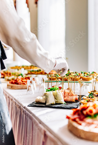 Obraz na plátně woman hands of a waiter prepare food for a buffet table in a restaurant