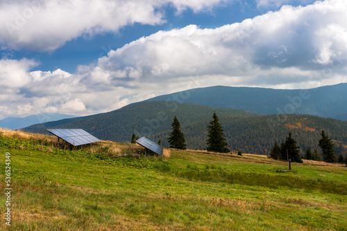 Photovoltaic panels in the mountains. Electric power supply for a mountain chalet. Beautiful mountain landscape in the background. Beskidy Mountains. Rysianka, Poland
