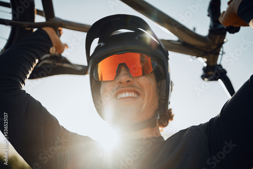 Cyclist, lift bike and smile for celebration after winning race, tour or competition with helmet on head. Man, bicycle and sunglasses after win in sports to show happiness in summer sunshine