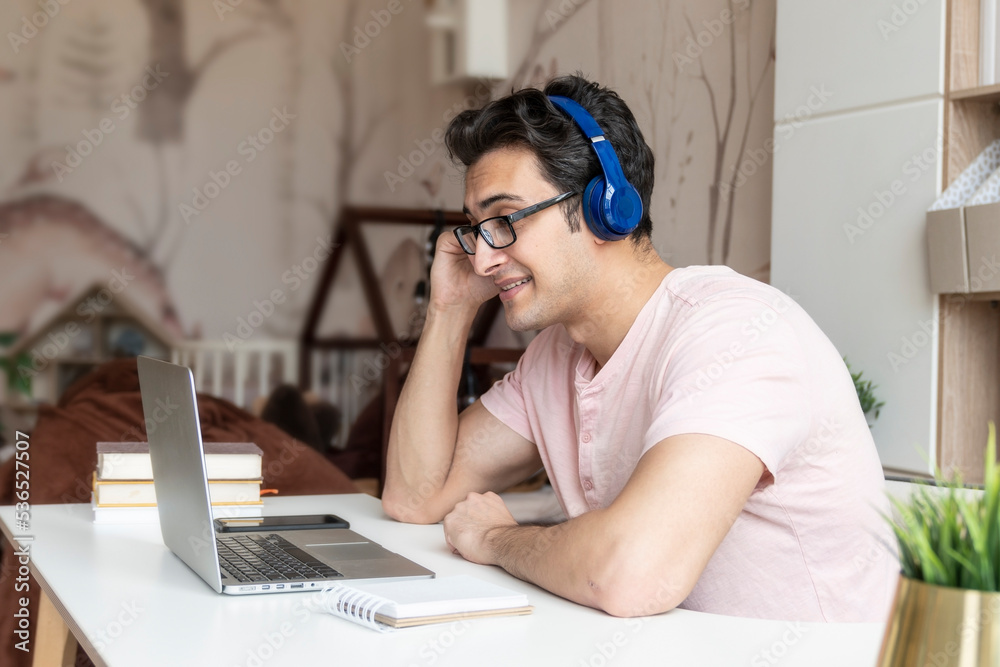Side view on young handsome man in headphones studying online at home. Distance education concept	