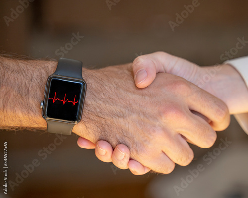 A close-up of a handshake and a smartwatch on a man's hand that shows a sign of a rapid heartbeat. A man is nervous when meeting a girl.