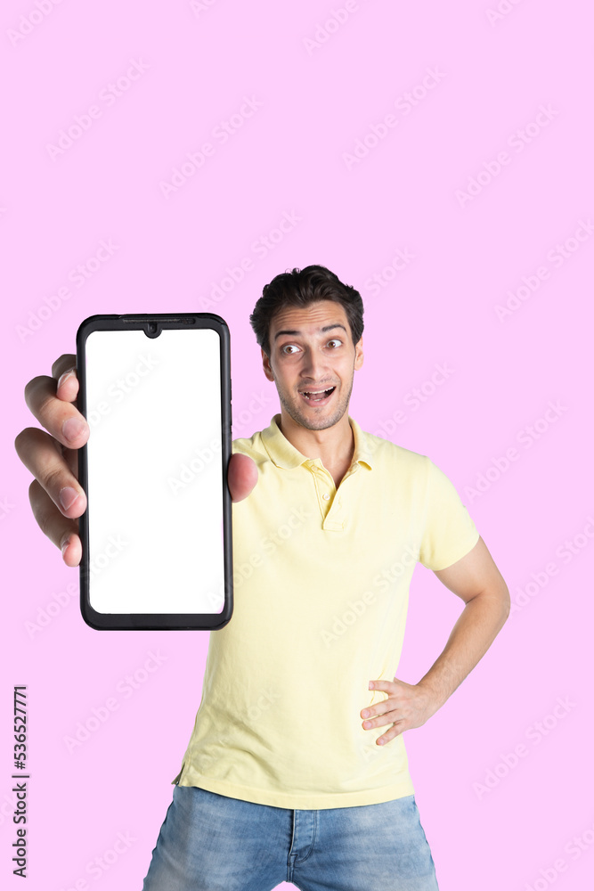 Handsome smiling man showing smartphone with white screen isolated on pink background. Mobile Application and advertising concept