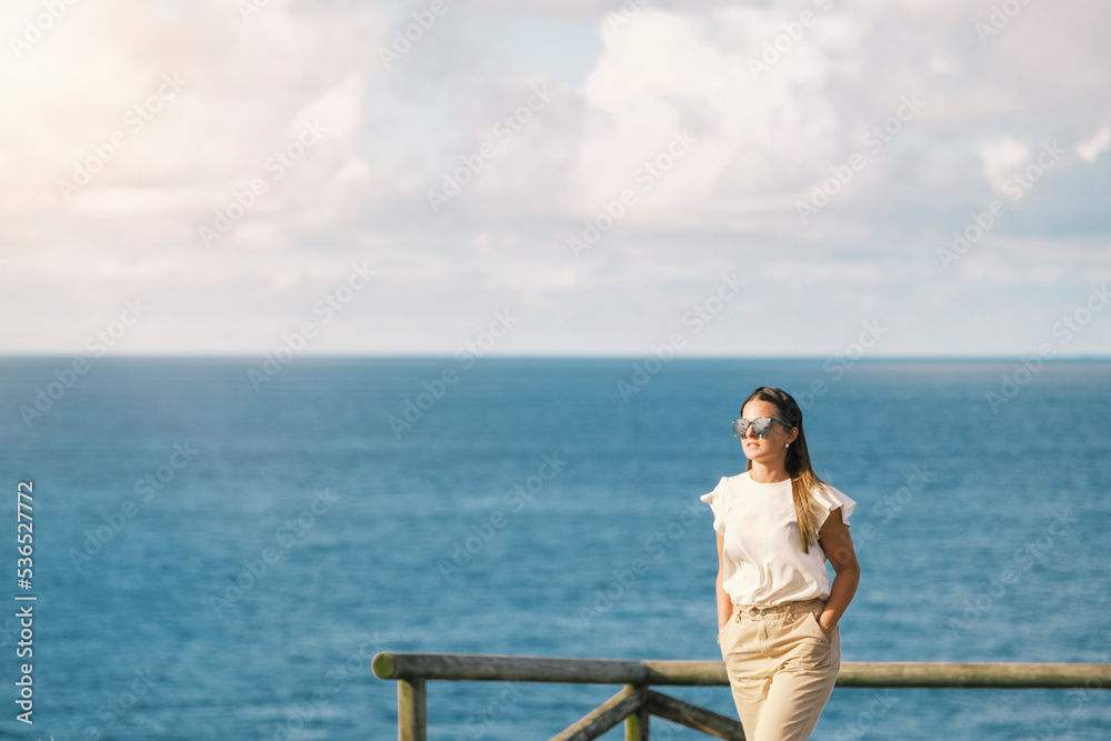 Mujer pasea por la costa viendo el mar