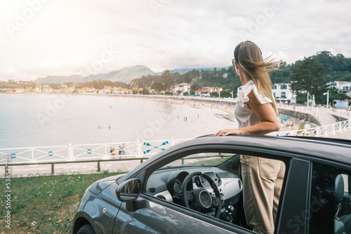Mujer en coche descapotable en la playa 