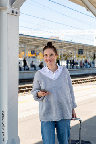 Train ride. Happy, smiling young woman on the station platform.