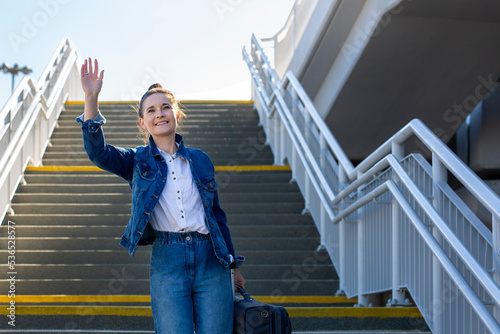  woman waves goodbye. A young woman says goodbye by waving her hand.