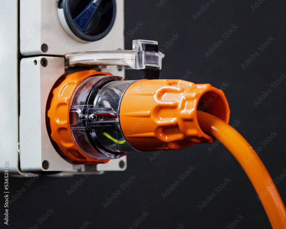 an orange industrial power plug on the wall an orange industrial power plug on the wall