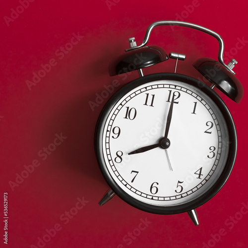 vintage old black alarm clock on red background 
