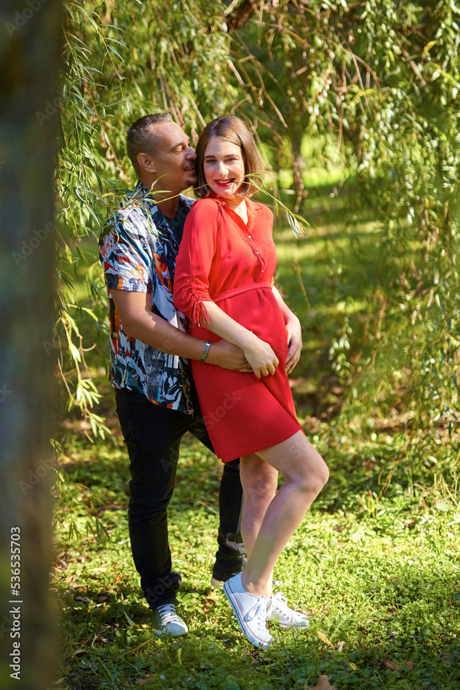 Fototapeta premium Lovely pregnant couple walking in a park