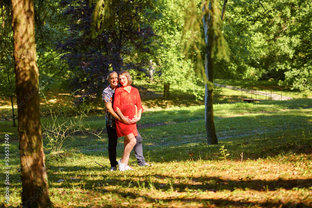 Lovely pregnant couple walking in a park Lovely pregnant couple walking in a park