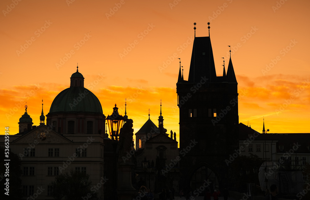 Spectacular sunrise in Prague, sun rising between the landmark towers from Charles Bridge during an unique autumn moment. Travel to Czech Republic.