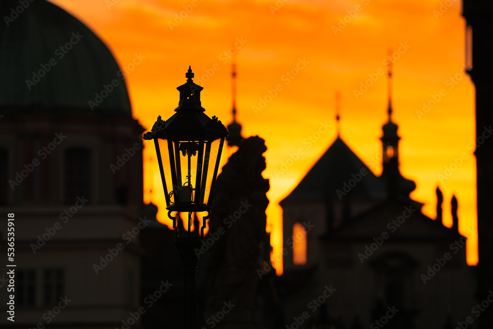 Spectacular sunrise in Prague, sun rising between the landmark towers from Charles Bridge during an unique autumn moment. Travel to Czech Republic.