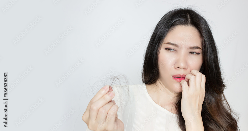 Asian beautiful woman is looking for her hair loss in her hand and raise another hand touch on lip with shocked and worry face. Asian beautiful woman is looking for her hair loss in her hand and raise another hand touch on lip with shocked and worry face.