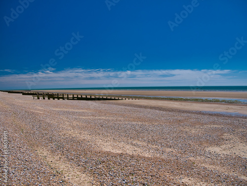 The open expanse of deserted shingle beach at Dungeness, Kent, UK. Taken on a sunny day in summer.