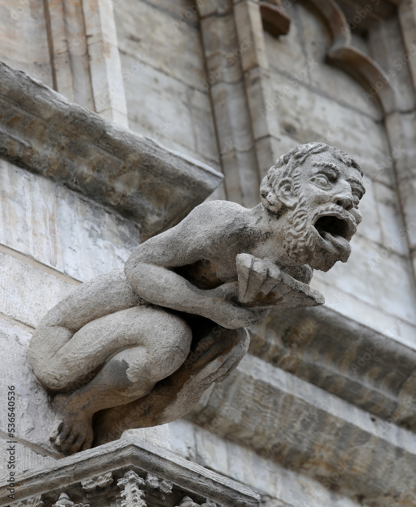 Monstrous statue with almost human features called gargoyle on the historic building
