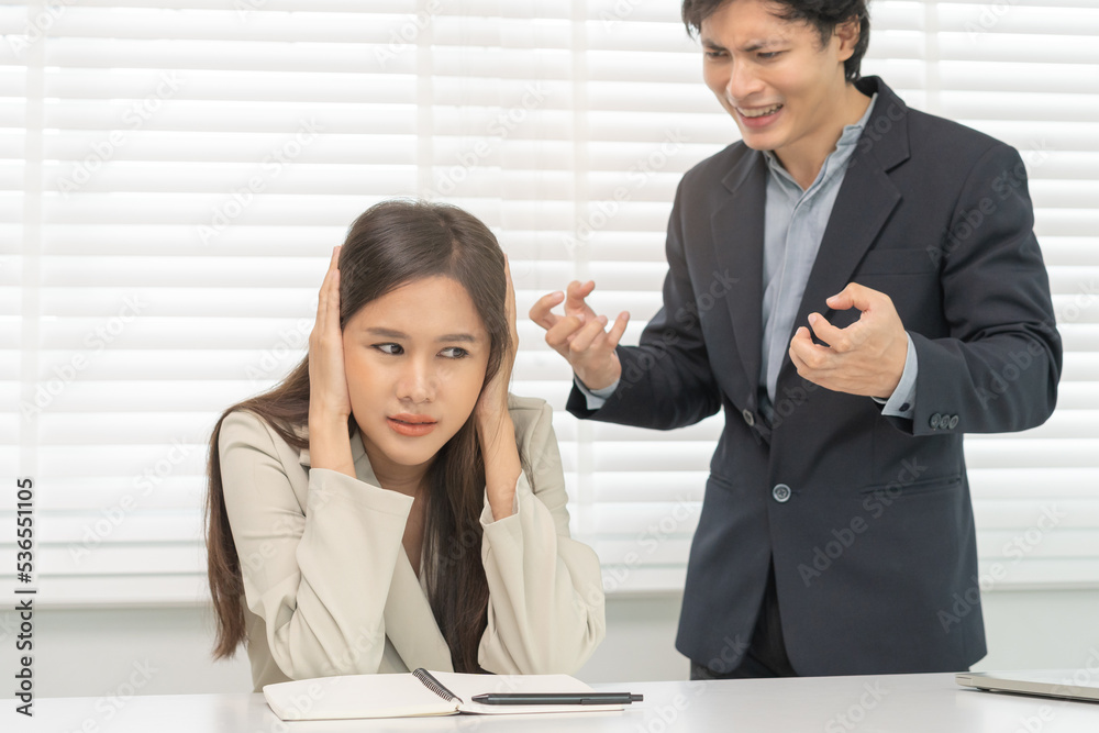 Angry boss, stressed asian young business, employee, secretary woman sitting at desk, hand cover her ears feel upset from annoying boss, colleague conflict with manager mistake about job at office. Angry boss, stressed asian young business, employee, secretary woman sitting at desk, hand cover her ears feel upset from annoying boss, colleague conflict with manager mistake about job at office.