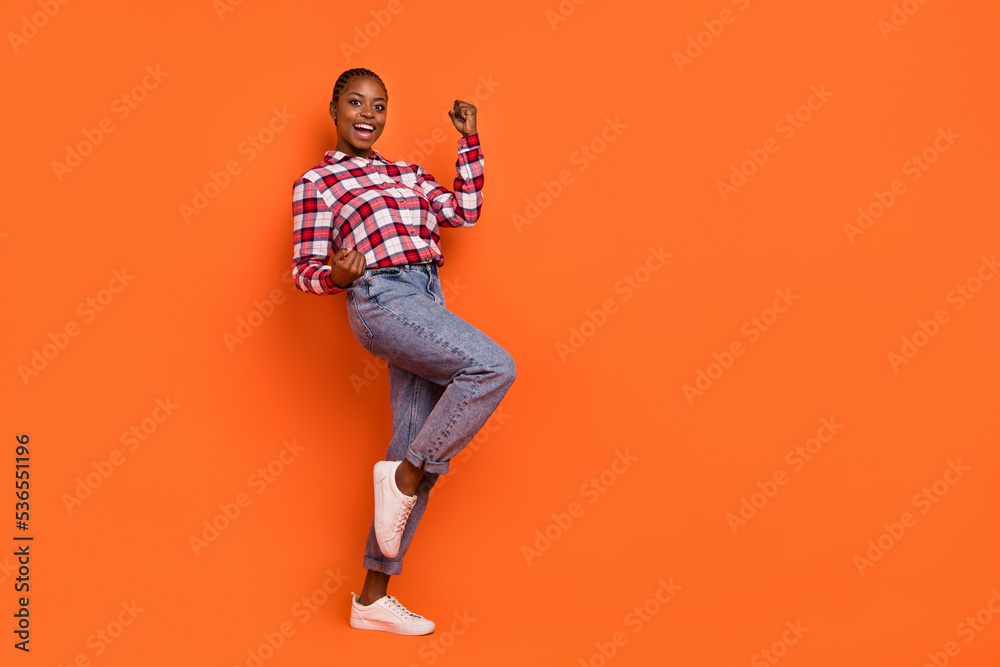 Fototapeta premium Full size portrait of delighted positive lady raise fists success achievement isolated on orange color background