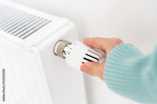 A woman's hand is holding on to a white heater. Heating concept