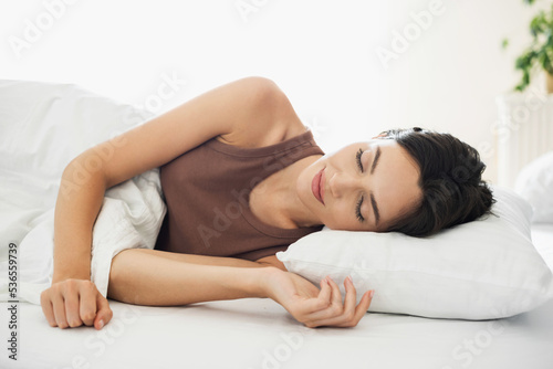 Young woman sleeping in bed. Cute woman in bedroom at home. Relaxation, resting, self care, healthy lifestyle, bedtime concept