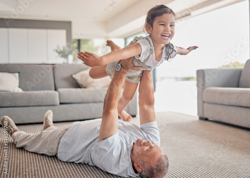 Love, happy grandfather and girl play in living room and laugh, fun and smile together. Grandparent lifting grandchild at home in lounge and enjoy bonding, carefree and relax on floor on weekend. photo