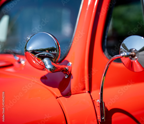 Closeup of a spotlight on a restored antique pickup truck at a car show on a sunny day.