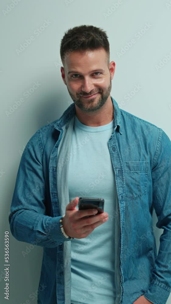 Portrait of happy casual man using phone, Young guy standing at white wall, smiling, Isolated on white background, blank copy space. Portrait of happy casual man using phone, Young guy standing at white wall, smiling, Isolated on white background, blank copy space.