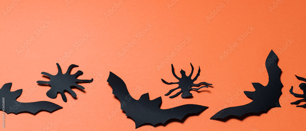 Halloween background with bats and spiders on orange background. Halloween paper decorations. Copy space Halloween background with bats and spiders on orange background. Halloween paper decorations. Copy space