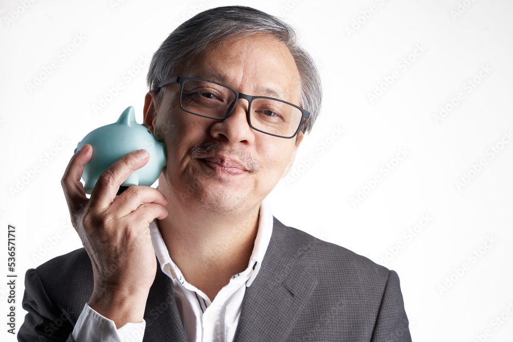 senior chinese man with formal wear eyeglasses holding piggy bank against white background senior chinese man with formal wear eyeglasses holding piggy bank against white background