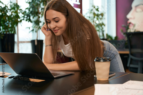Joyous female office worker reading email on portable computer