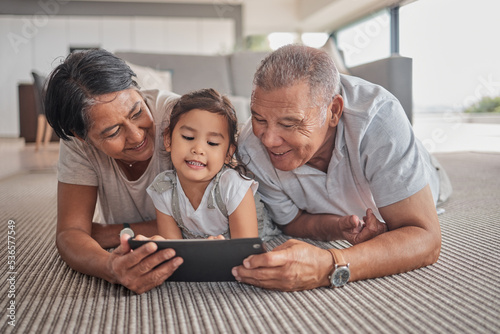 Photos Relax, grandparents and cartoon on tablet with child on home floor together in the Philippines