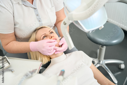 Woman dentist putting aligners on her teeth