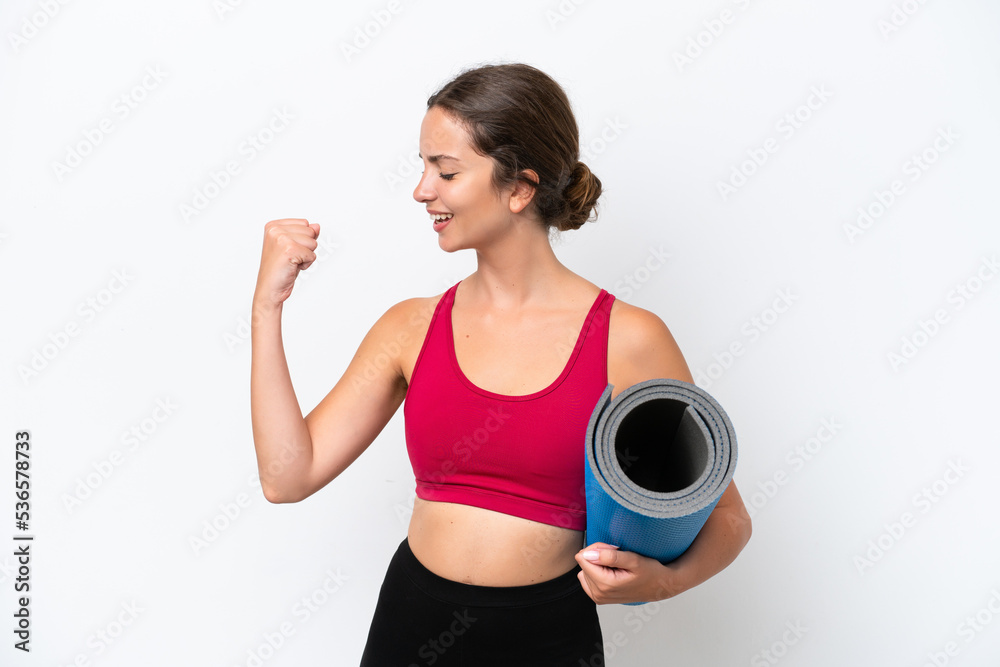 Young sport caucasian woman going to yoga classes while holding a mat isolated on white background celebrating a victory Young sport caucasian woman going to yoga classes while holding a mat isolated on white background celebrating a victory