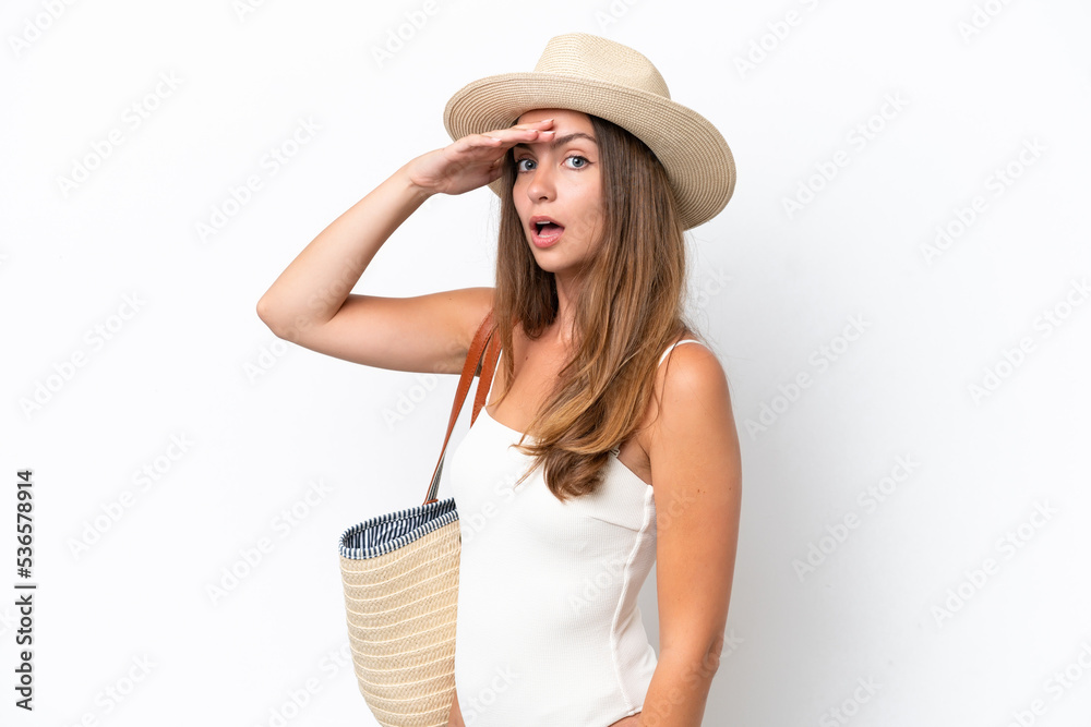 Young caucasian woman in swimsuit in summer holidays isolated on white background doing surprise gesture while looking to the side