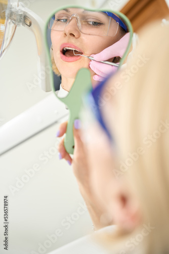 Caucasian woman in glasses looks in the mirror