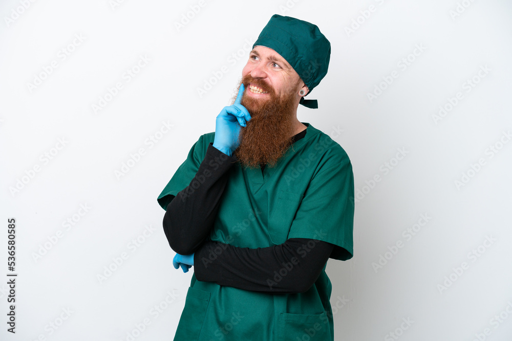Surgeon redhead man in green uniform isolated on white background thinking an idea while looking up Surgeon redhead man in green uniform isolated on white background thinking an idea while looking up