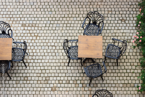 Top view of chairs and wooden table in the cafe garden outside. Stone floor. Authentic restaurant concept.