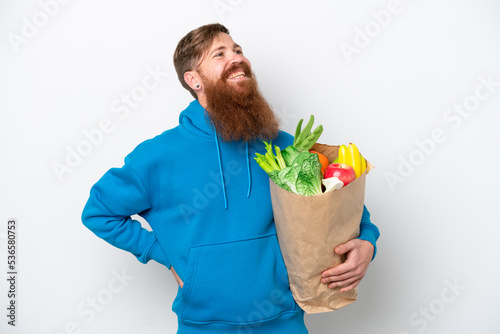 Redhead man with beard holding a grocery shopping bag isolated on white background looking side