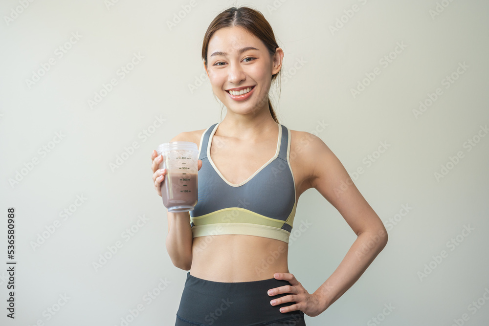 Diet meal replacement for weight loss, happy asian young woman, girl in sportswear, hand in holding protein shake bottle for drink supplement for muscle after workout at home. Healthy body care person Diet meal replacement for weight loss, happy asian young woman, girl in sportswear, hand in holding protein shake bottle for drink supplement for muscle after workout at home. Healthy body care person