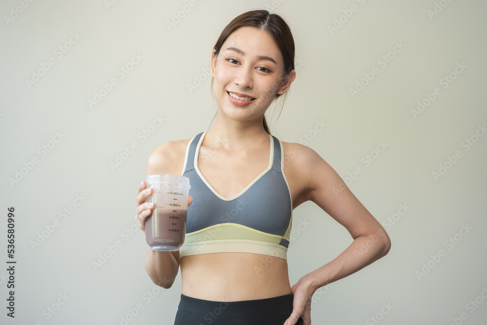 Diet meal replacement for weight loss, happy asian young woman, girl in sportswear, hand in holding protein shake bottle for drink supplement for muscle after workout at home. Healthy body care person Diet meal replacement for weight loss, happy asian young woman, girl in sportswear, hand in holding protein shake bottle for drink supplement for muscle after workout at home. Healthy body care person