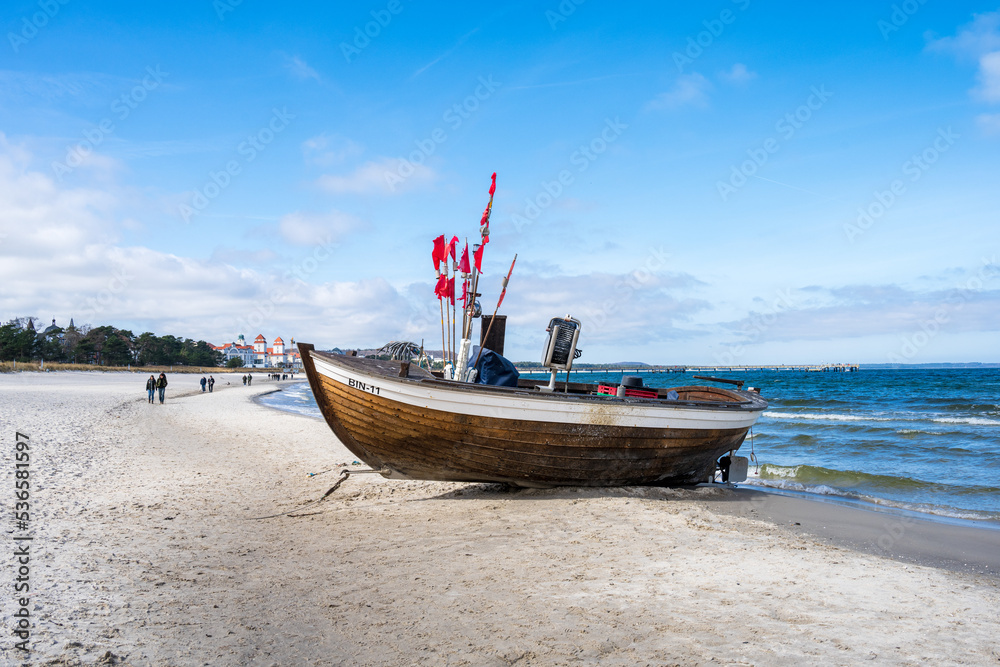 Ostseebad Binz an einem sonnigen Winternachmittag ein Fischerboot liegt am Strand - obrazy, fototapety, plakaty 