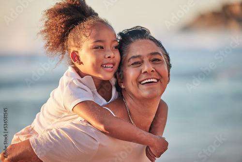 Family, children and beach with a girl and grandmother outdoor by the sea or ocean during summer. Happy, smile and face with a woman and granddaughter spending time outside together in nature © Alexis Scholtz/peopleimages.com