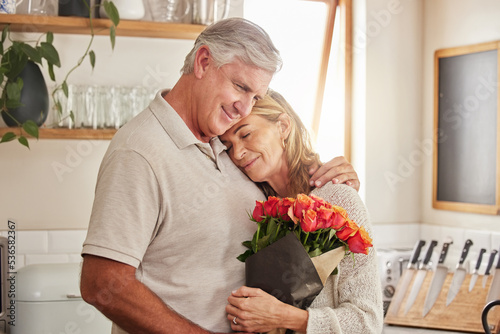 Flower bouquet, hug and senior couple in celebration of love, marriage and anniversary in their house. Happy elderly man and woman hugging with rose flowers for gift or present for birthday in home