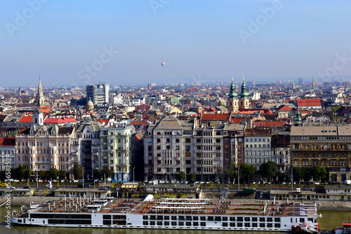 Budapest skyline with residential buildings along the Danube river. white hotel boats moored along the river shore. residential apartment buildings. day traffic. travel and tourism concept