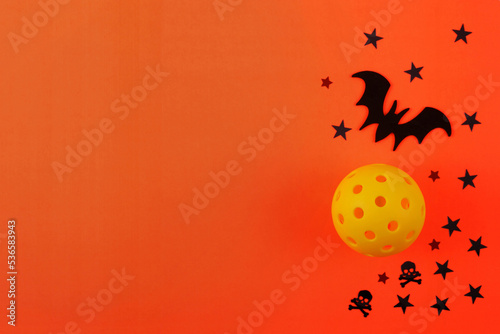 Pickleball Haloween with orange background, yellow Pickleball, black Bat and stars. Lots of room for text.